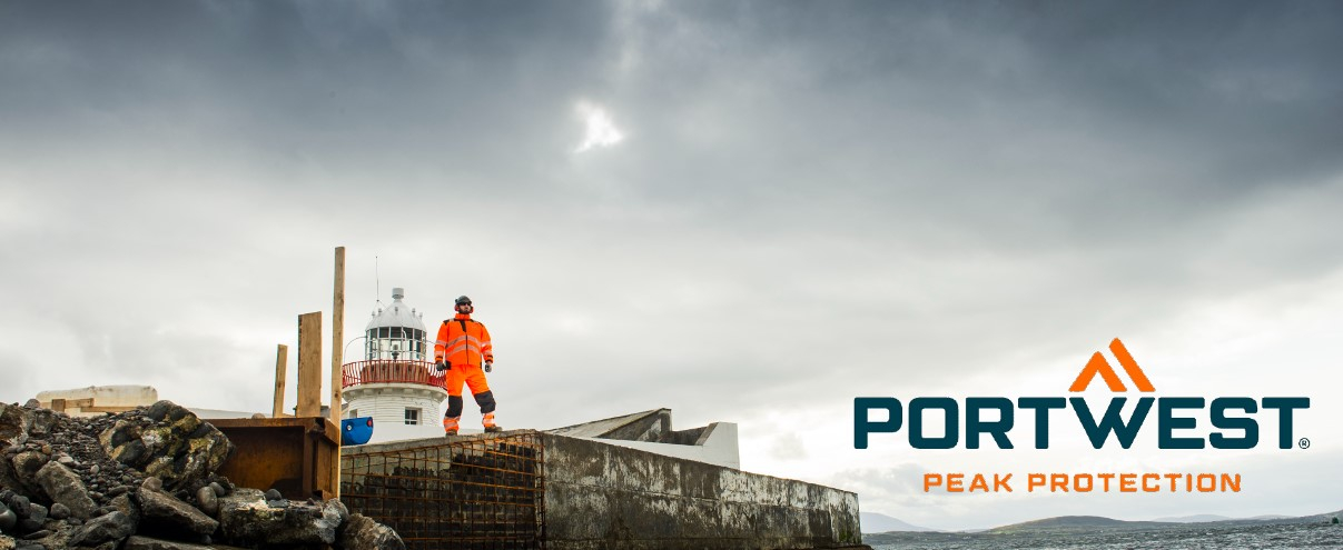 A worker in orange high visibility clothing stands on a rocky construction site next to a lighthouse, with the Portwest logo and the slogan 'Peak Protection' in the picture.