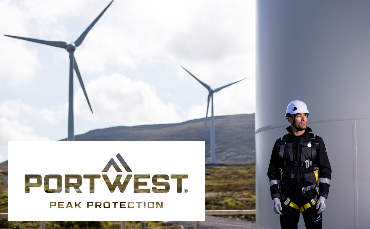 A worker wearing full fall protection equipment is standing next to a wind turbine. More wind turbines can be seen in the background. The Portwest logo with the slogan 'Peak Protection' is displayed in the foreground. A link to our fall protection is provided.