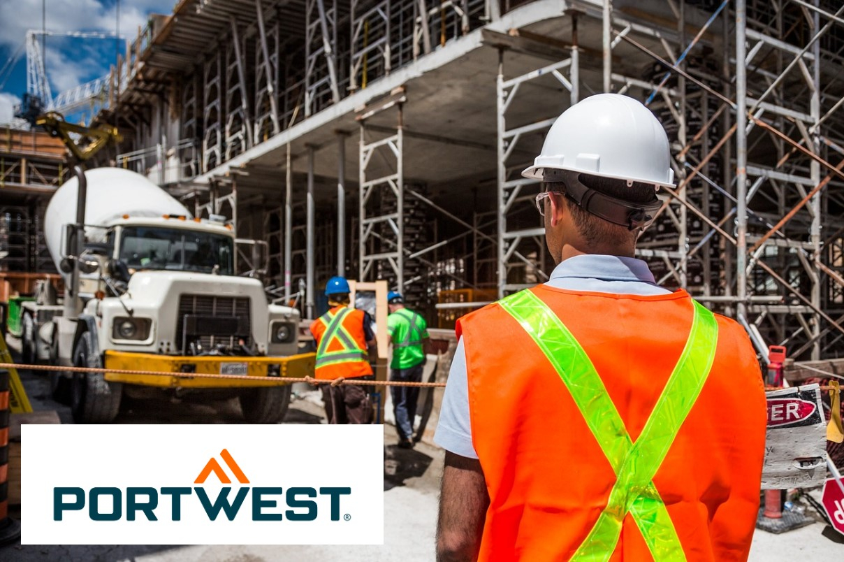 A construction worker with a white hard hat and orange high visibility vest with reflective stripes is standing on a construction site. In the background you can see other workers, a concrete mixer and scaffolding. Portwest logo visible in the corner. A link to the selection of different high visibility clothing is provided.